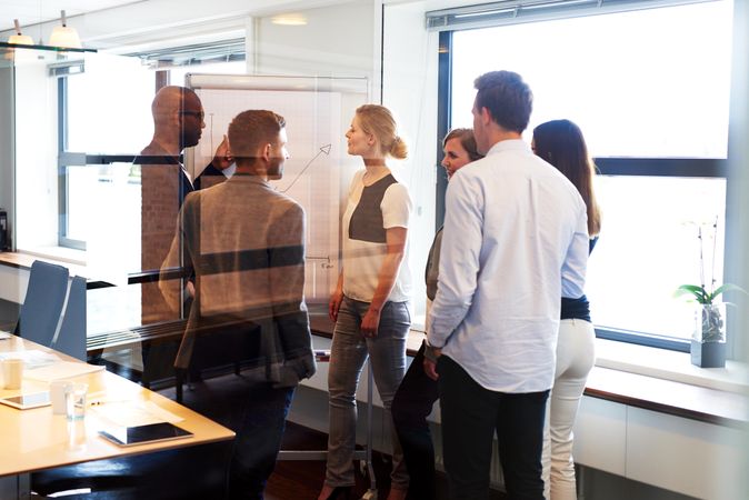 Multi-ethnic group of business associates looking over a chart on a presentation board