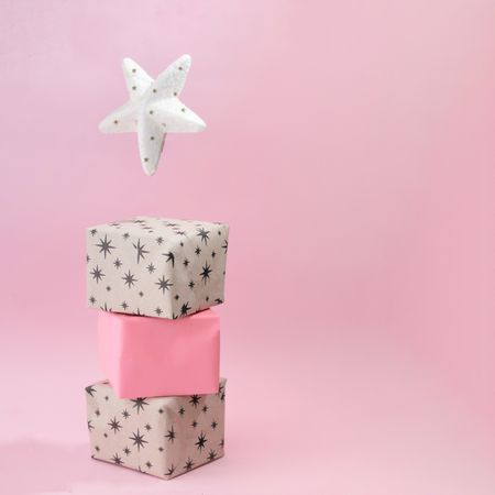 Christmas presents piled on soft pink background