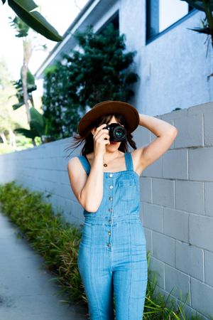 Female photographer in hat and denim one piece