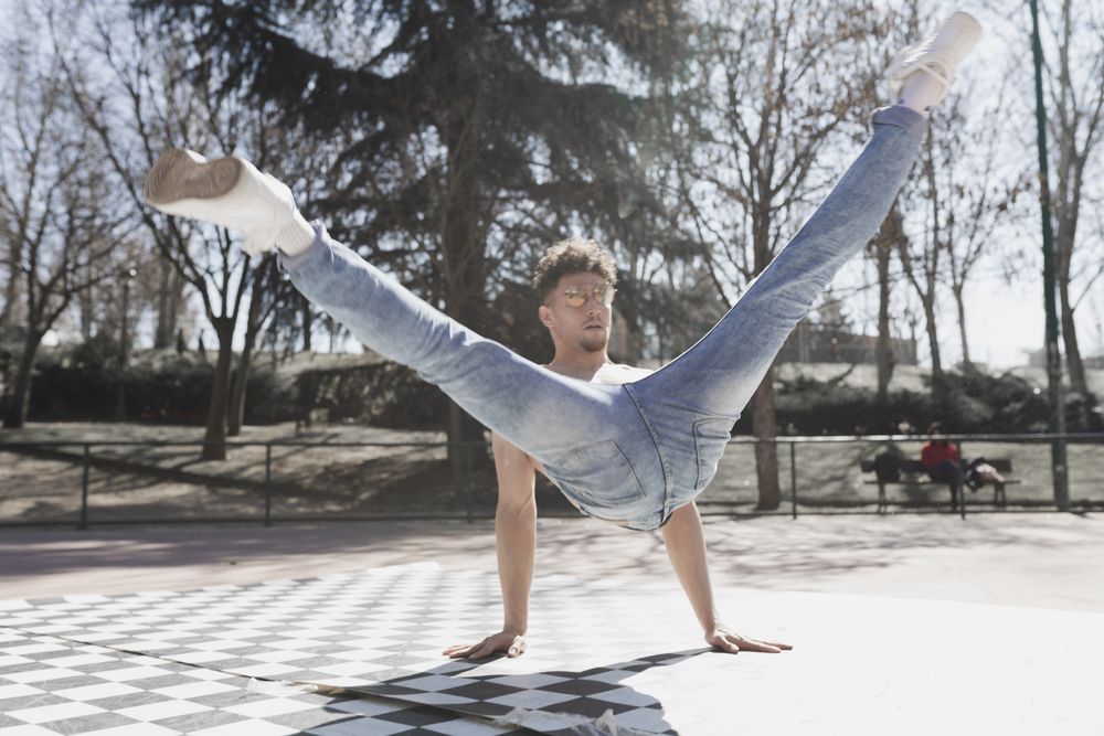 Shirtless man dancing break dance in park