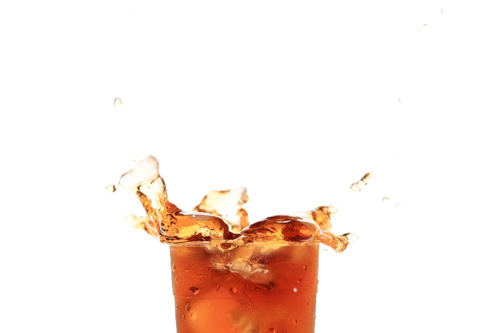 Close Up Splash of Iced Tea on Plastic Cup Isolated on Plain Background.