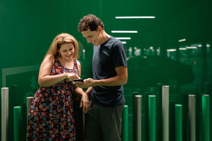 Couple browsing smartphone on green parking lot