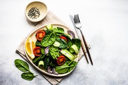 Leafy spinach salad with cherry tomatoes served with sesame seeds