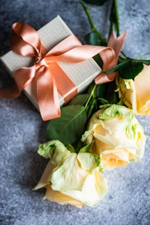 Yellow flower on grey table with small giftbox