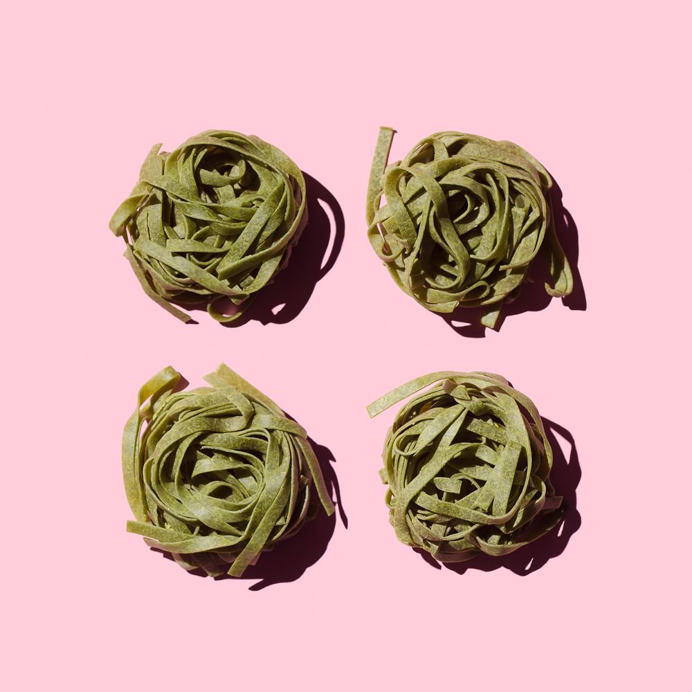 Green bird's nest pasta organized over pink background