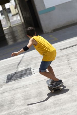Back view of a male skateboarder riding on a sunny day