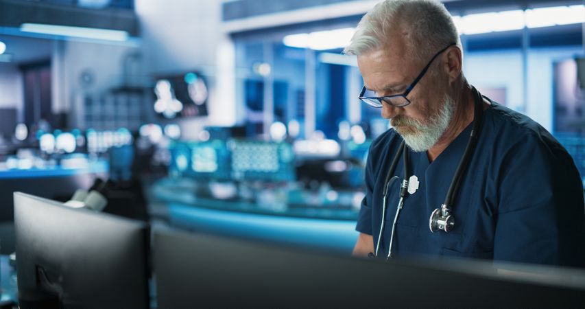 White Male Doctor Using Desktop Computer In Modern Hospital Medical Research Laboratory.