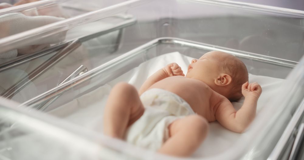 Cute Emotional Newborn Little Infant Lying in Hospital Cot.