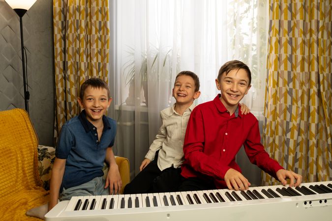 Three boys happily gathered around piano