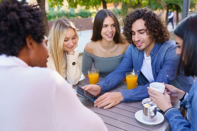 Multi-ethnic group of friends having coffee and juice outside