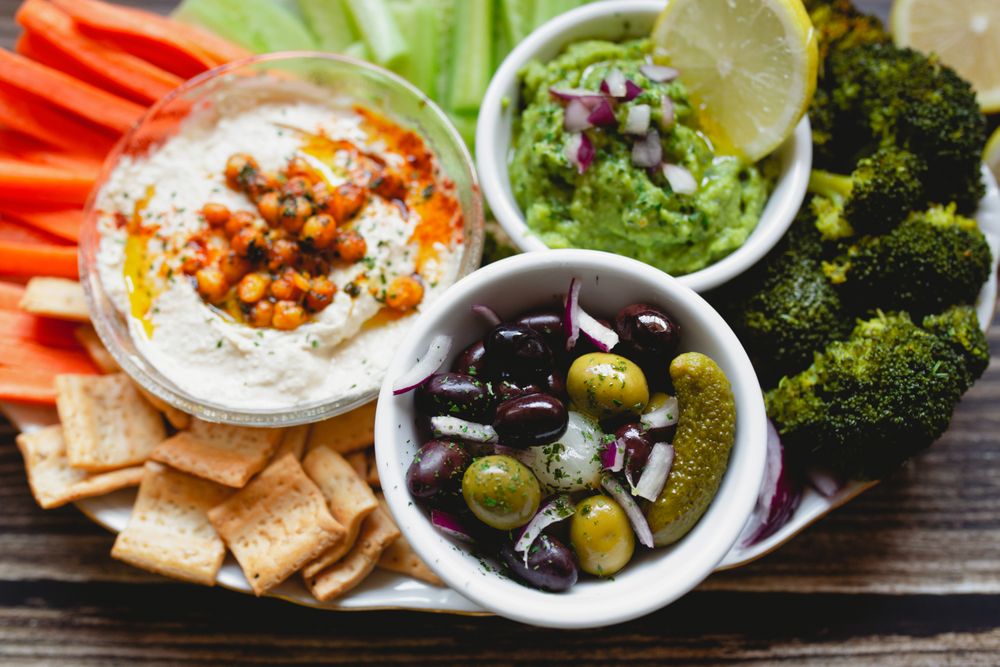 Tasty hummus and sauces decorated with bright cut vegetables on table