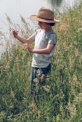 Boy among tall grass near river