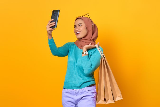 Muslim woman taking a video call while holding shopping bags