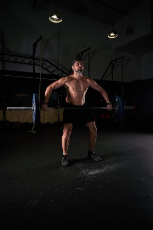 Muscular professional male athlete lifting barbell with weights