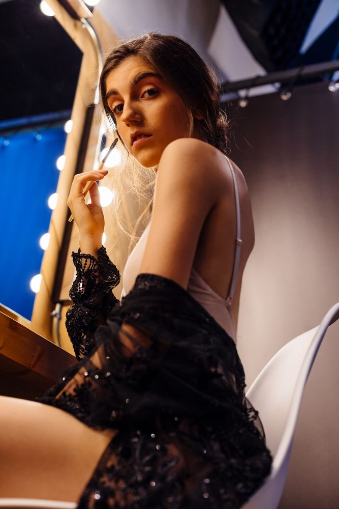 Chic female in transparent dress looking in mirror