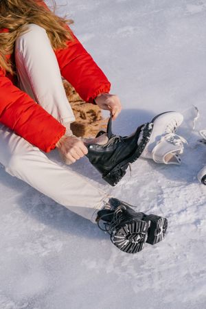 Woman sitting on snow and changing boots