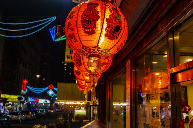 Lit red lanterns hanging beside window in the city at night