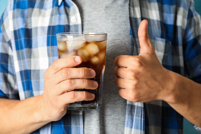 Male hand holding a glass with cola, close up