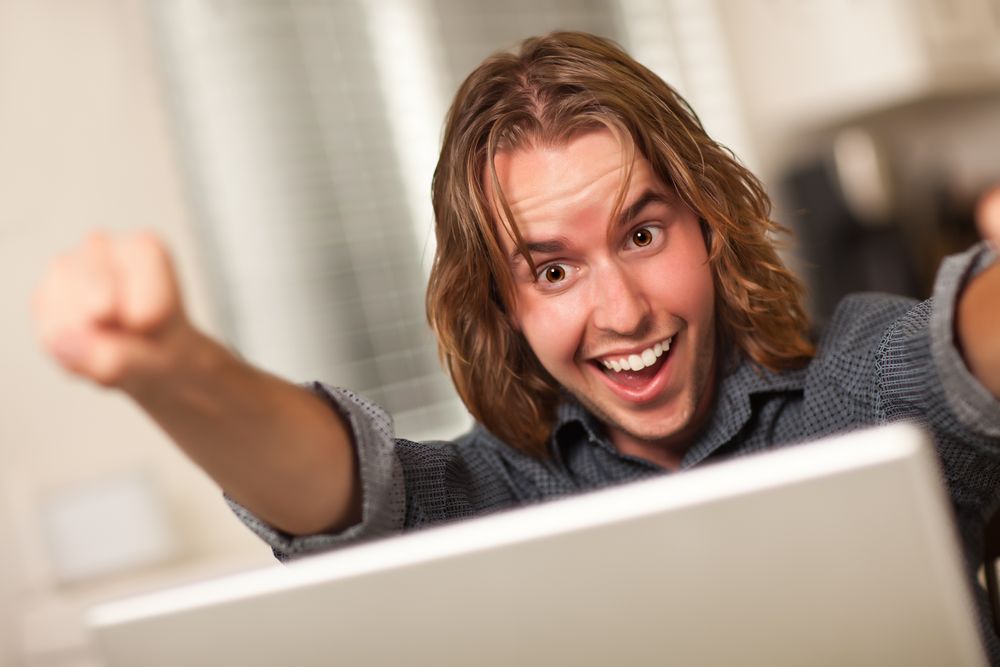 Cheering Young Man Using Laptop Computer