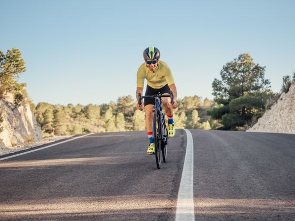 healthy man riding a bicycle on a mountain road in a sunny day