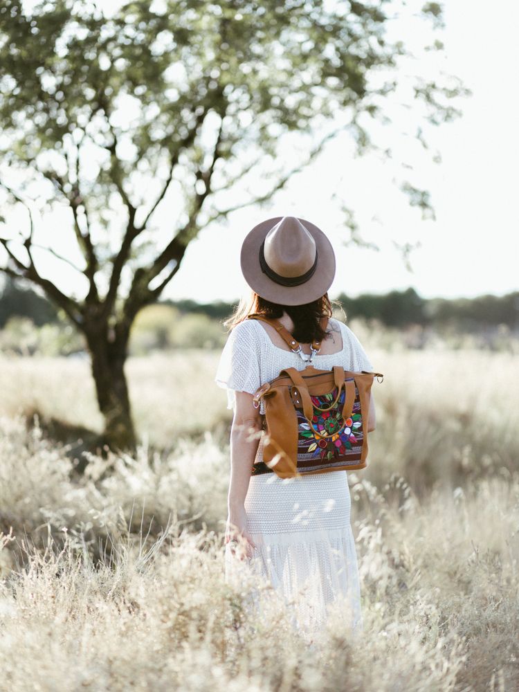 Female traveller with colorful backpack walking on field