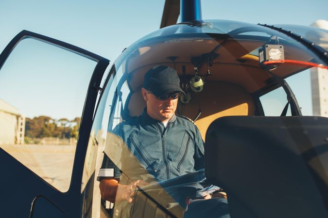 Helicopter on airport ground with pilot waiting in cockpit