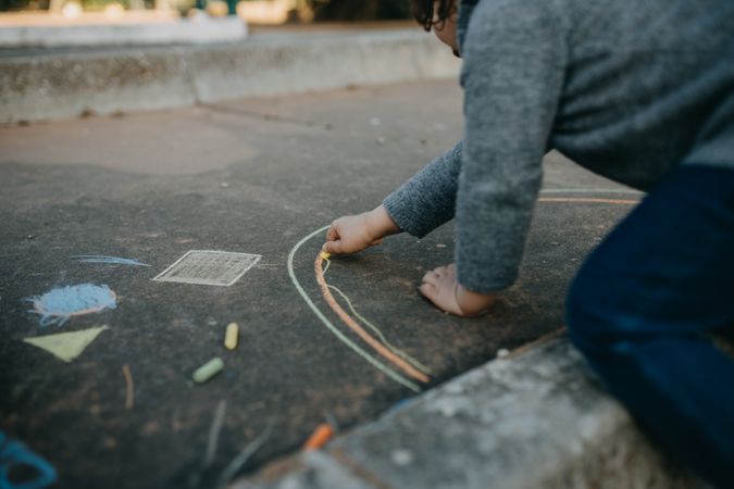 Child drawing rainbow with chalk