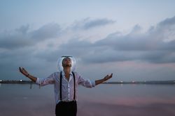 Man with fish tank on head standing at seashore