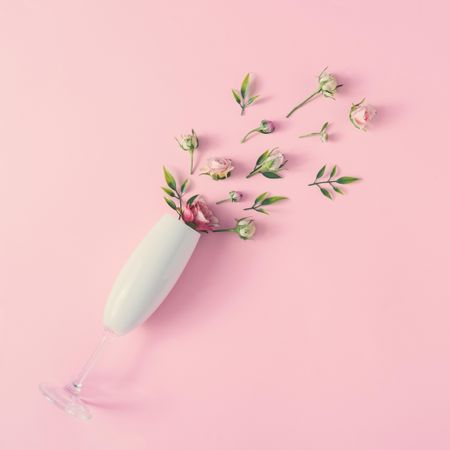 Champagne glass with spring flowers against pink background