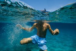 Unrecognizable kid swimming in sea
