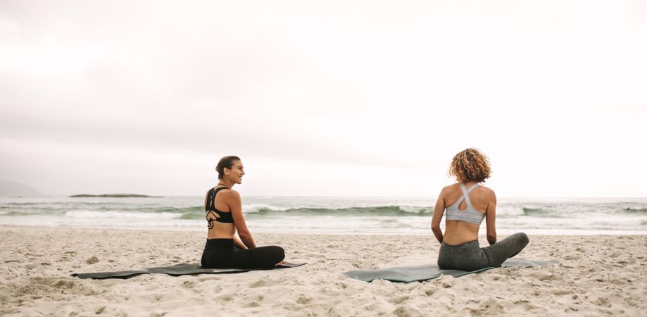 Fitness women doing yoga facing the sea