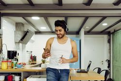 Young male with smartphone and cup of tea