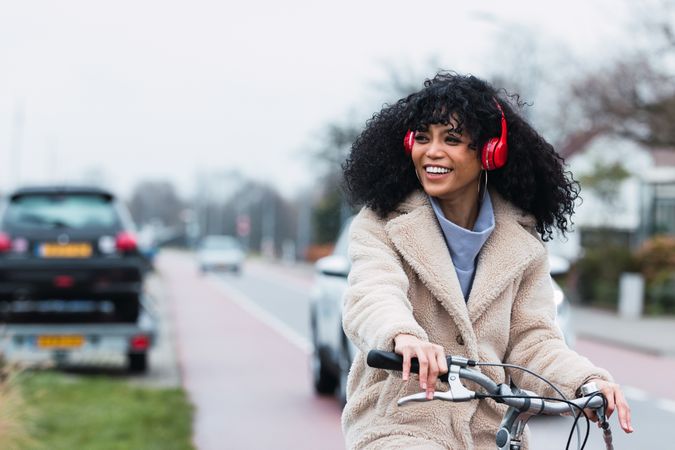 Excited Black woman in headphones riding bicycle