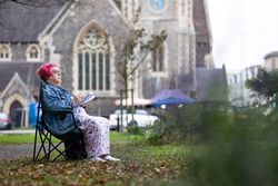 Side view of woman sitting outside church and drawing