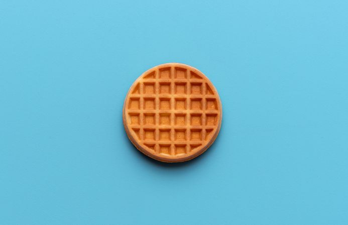 Round waffle directly above view, isolated on a blue background
