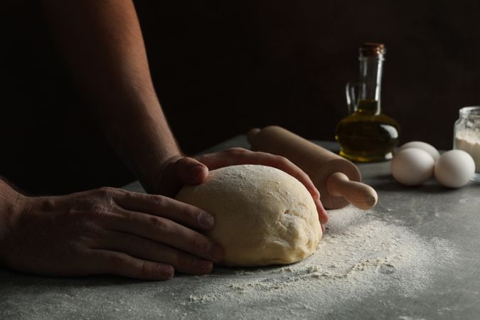 Man cooking dough on gray table, close up