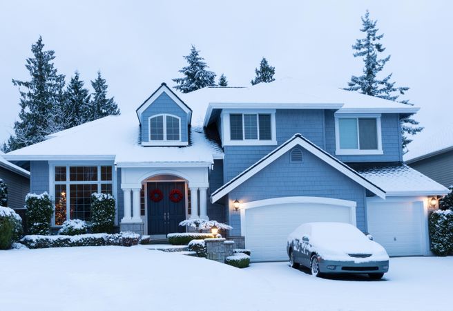 Front of suburban home decorated for the holidays with fresh snow