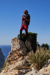 Male hiker with backpack standing on rocky cliff