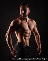 Bodybuilder competitor practicing upper body poses in dark studio 4BloM0