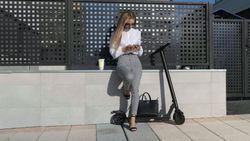Businesswoman with mobile and her scooter next