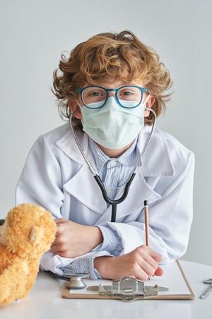 Boy doctor in sterile mask with stethoscope and toy bear