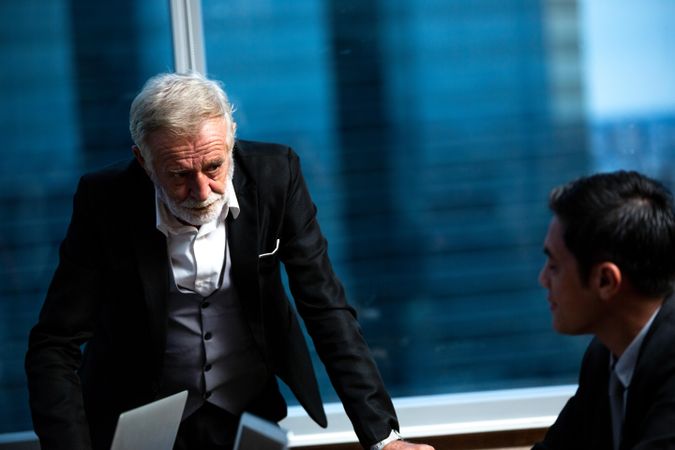Man in suit discussing a project with colleague in a meeting room