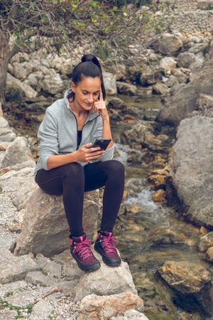 Smiling woman using smartphone near creek