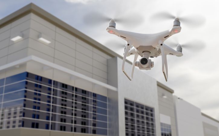 Unmanned Aircraft System Quadcopter Drone UAV In The Air Near Corporate Industrial Building