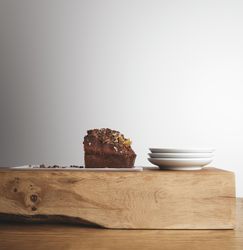 Side view of chocolate cake and plates on wooden board