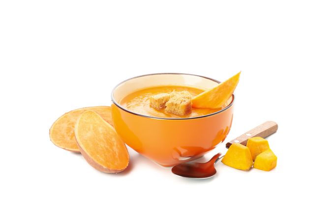 Bowl of sweet potato soup with croutons and spoons