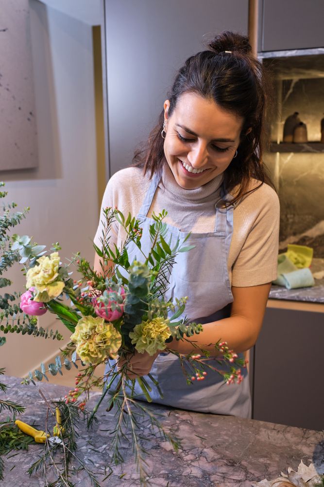 Happy female florist composing bouquet