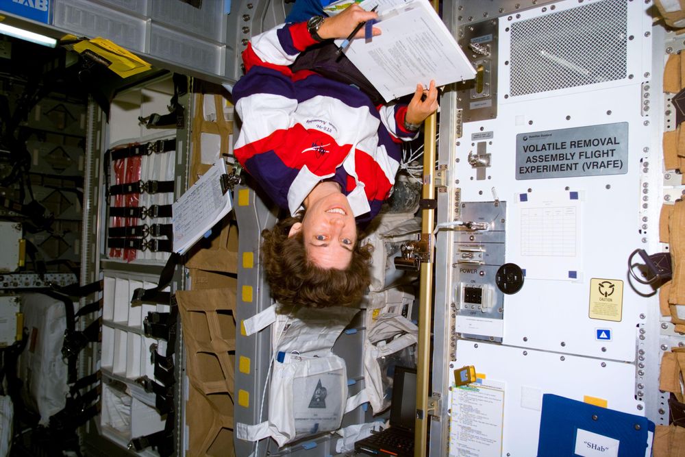Mission specialist Ellen Ochoa beside the Volatile Removal Assembly Flight Experiment