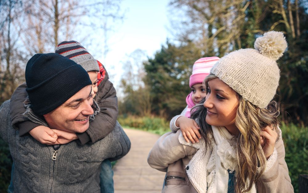 Happy mother and father giving daughter and son piggy back in forest