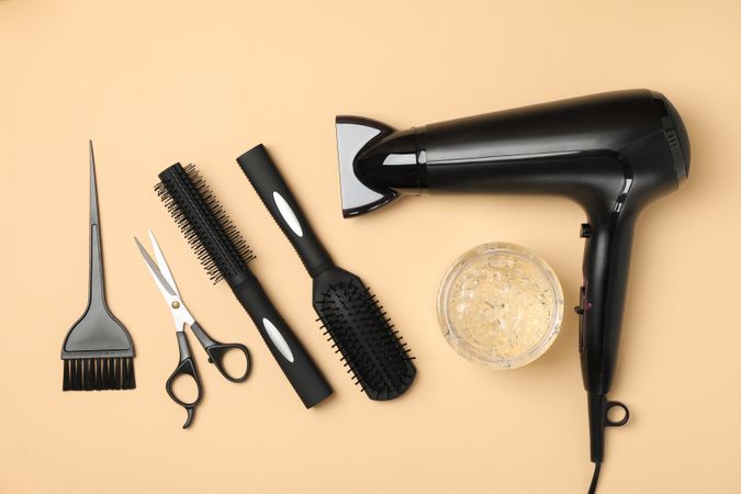 Composition with hairdresser accessories on beige background, top view